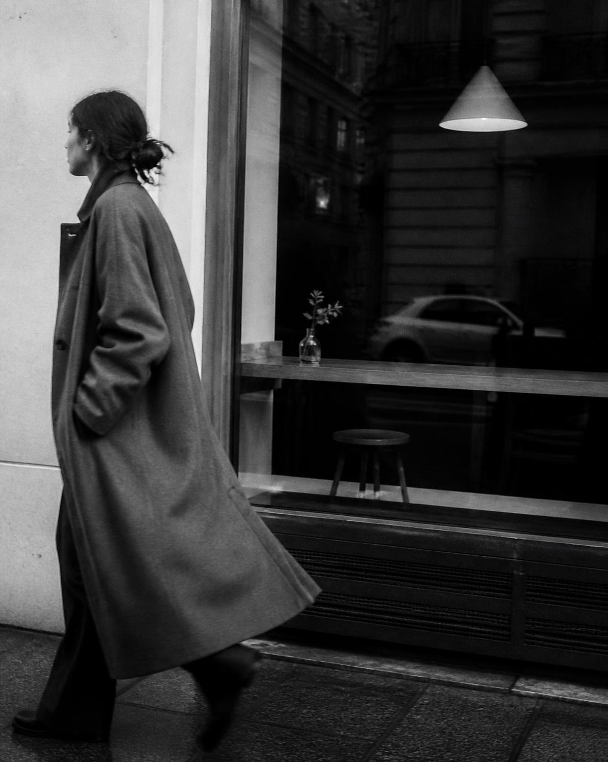 Person in a long coat walking past the cafe window